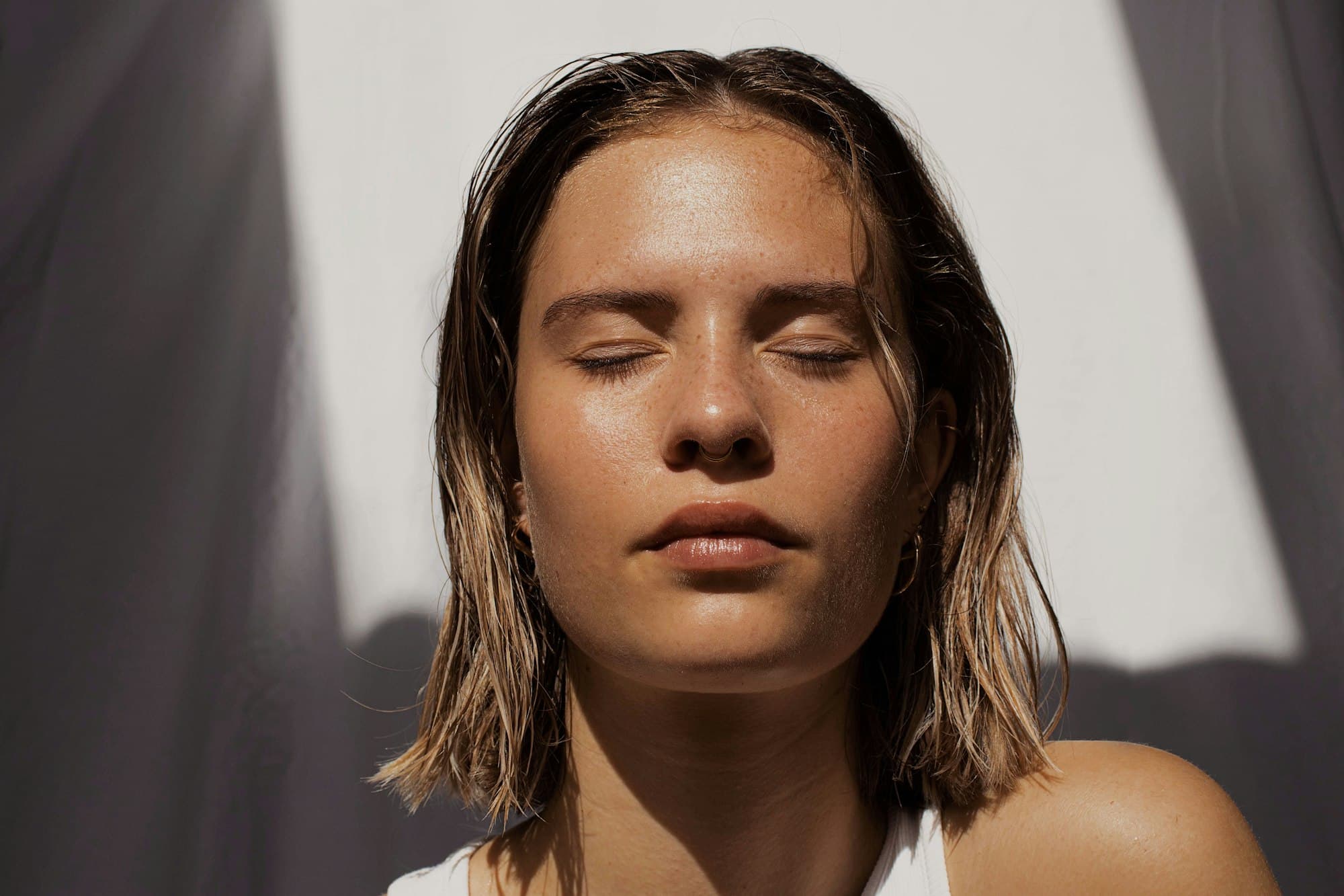 A woman's face in bright natural light, eyes closed
